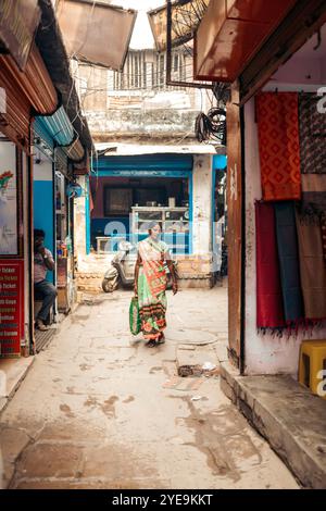 Femme marchant dans une rue étroite près des magasins à Varanasi, Inde ; Varanasi, Uttar Pradesh, Inde Banque D'Images