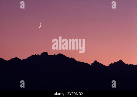 Lune dans le ciel rose au-dessus de la crête montagneuse silhouette dans l'est de la Sierra Nevada de Californie, États-Unis ; Californie, États-Unis d'Amérique Banque D'Images