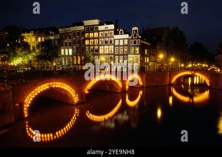 Arcs de pont le long d'un canal illuminé la nuit à Amsterdam, pays-Bas ; Amsterdam, pays-Bas Banque D'Images