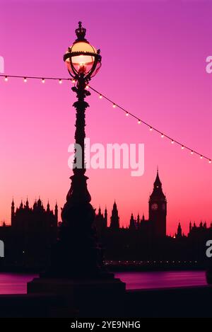 Maisons du Parlement au crépuscule à Londres, avec un ciel rose éclatant vibrant et un bâtiment silhouette à travers l'horizon, et une lampe décorative standard... Banque D'Images