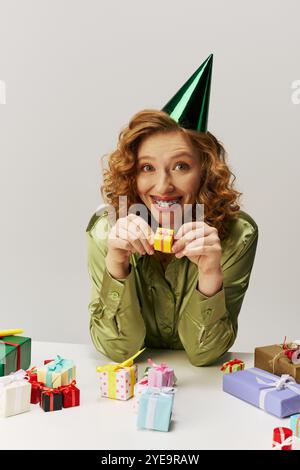 Une jeune femme joyeuse pose avec excitation, entourée de cadeaux colorés. Banque D'Images