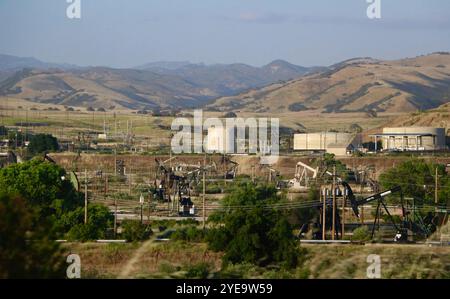 Paysage avec des collines et des Pumpjacks ou des pompes à balancier et des réservoirs de stockage de pétrole brut dans un champ pétrolier Californie USA Banque D'Images