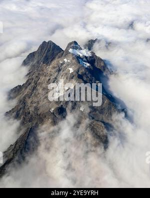 Aérien de sommets montagneux à travers les nuages brumeux, vu du vol de Calgary, Alberta à Vancouver, Colombie-Britannique ; Canada Banque D'Images