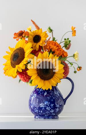 Bel arrangement floral avec tournesols et fleurs orangées dans un vase bleu ; Surrey, Colombie-Britannique, Canada Banque D'Images