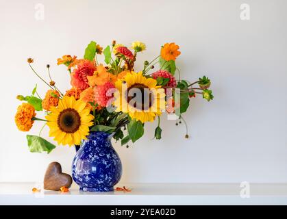 Bel arrangement floral avec tournesols et fleurs orangées dans un vase bleu ; Surrey, Colombie-Britannique, Canada Banque D'Images