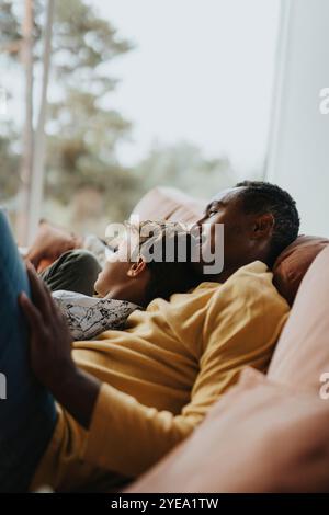 Père et fils penchés sur le canapé dans le salon à la maison Banque D'Images