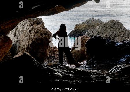 Femme se tient sur les rochers à marée basse dans la grotte de Lapa de Santa Margarida ; Sao Lourenco, Setubal, Portugal Banque D'Images