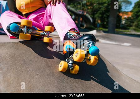Femme portant des patins à roulettes avec des roues jaunes et des rayures arc-en-ciel Banque D'Images