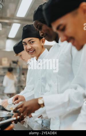 Adolescent souriant pratiquant avec des stagiaires masculins et féminins dans la cuisine commerciale Banque D'Images