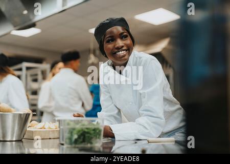 Heureuse stagiaire féminine s'appuyant sur le comptoir de cuisine Banque D'Images