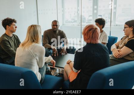 Professionnel de la santé mentale discutant avec des étudiants de sexe masculin et féminin pendant la thérapie de groupe Banque D'Images