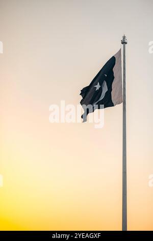 Drapeau national du Pakistan dans un ciel de coucher de soleil à la frontière Attari - Wagah ; Wagah, Lahore, Pakistan Banque D'Images