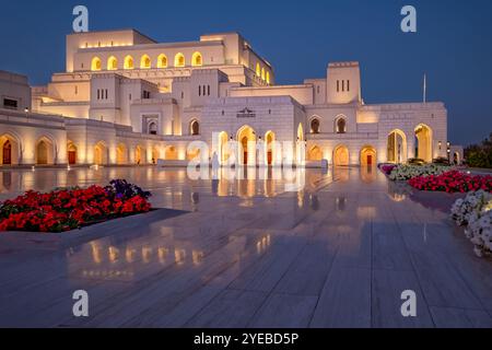 Le Royal Opera House Muscat magnifiquement illuminé la nuit, reflétant élégamment sur les sols polis. Banque D'Images