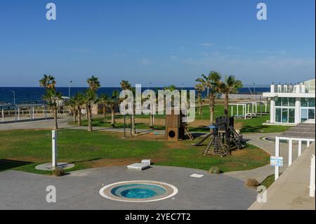 Les familles apprécient les activités de plein air dans un parc verdoyant surplombant l'océan bleu tranquille par une journée ensoleillée. Banque D'Images