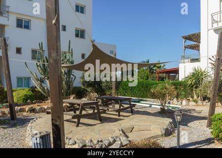 Une zone de rassemblement ombragée confortable avec des bancs en bois et des tables nichées dans un jardin, se prélasser au soleil. Banque D'Images