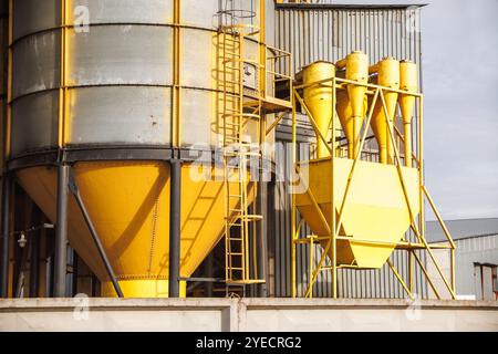 grand élévateur de grain avec plusieurs silos métalliques cylindriques, éléments structurels et un système complexe de tuyaux. Il se tient contre un ciel bleu, avec un f Banque D'Images