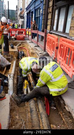 Travailleurs travaillant sur les câbles électriques des infrastructures de services publics creusant sous le trottoir dans Smithfield Charterhouse Street Londres Angleterre KATHY DEWITT Banque D'Images