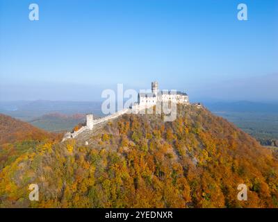 Le château médiéval de Bezdez se dresse fièrement au sommet d'une colline, entouré d'un feuillage d'automne vibrant. Le paysage présente un mélange étonnant de couleurs, reflétant la beauté de la saison. Banque D'Images