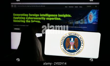 Personne tenant un smartphone avec le logo de la National Security Agency (NSA) sur l'écran devant le site Web. Concentrez-vous sur l'affichage du téléphone. Banque D'Images