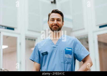 Portrait d'un professionnel de la santé masculin souriant portant des gommages bleus à l'hôpital Banque D'Images