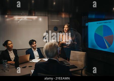 Femme d'affaires mature donnant la présentation tout en discutant des idées avec des collègues masculins et féminins Banque D'Images