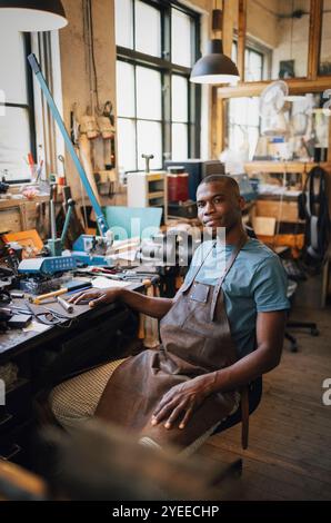 Portrait d'un jeune artisan masculin assis sur une chaise à l'atelier Banque D'Images