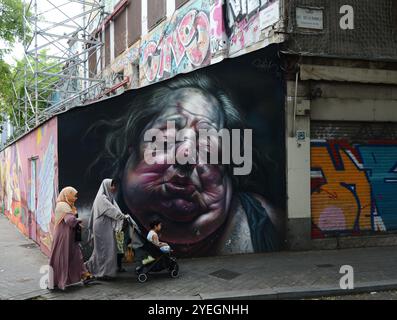 Femmes musulmanes marchant près d'une belle murale sur le mur Graffiti sur Carrer Nou de la Rambla à Barcelone, Espagne. Banque D'Images