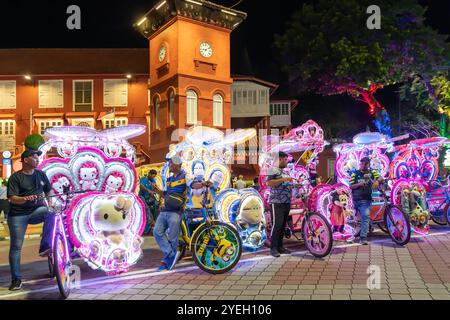 Malacca, Malaisie - septembre 20,2024 : Une rangée de pousse-pousse décorés d'un parking lumineux coloré devant la place néerlandaise la nuit Banque D'Images