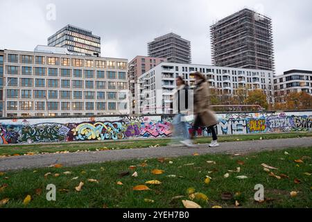 Berlin, Allemagne. 29 octobre 2024. Les gens marchent le long de la partie du mur de Berlin qui est maintenant l'East Side Gallery. Crédit : Sebastian Gollnow/dpa/Alamy Live News Banque D'Images