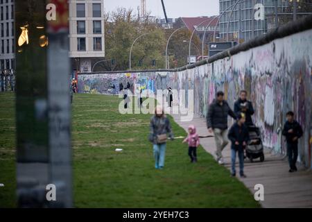 Berlin, Allemagne. 29 octobre 2024. Les gens marchent le long de la partie du mur de Berlin qui est maintenant l'East Side Gallery. Crédit : Sebastian Gollnow/dpa/Alamy Live News Banque D'Images