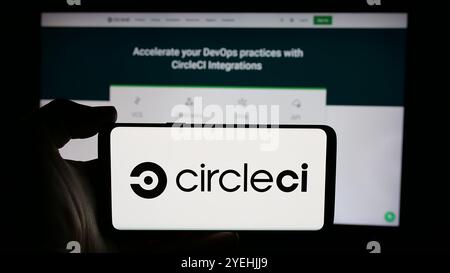 Personne tenant un téléphone cellulaire avec le logo de Circle Internet services Inc (CircleCI) sur l'écran devant la page Web de l'entreprise. Concentrez-vous sur l'affichage du téléphone. Banque D'Images