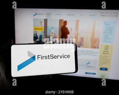 Personne tenant un téléphone intelligent avec le logo de la société canadienne FirstService Corporation sur l'écran devant le site Web. Concentrez-vous sur l'affichage du téléphone. Banque D'Images