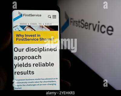 Personne tenant le téléphone cellulaire avec la page Web de la société canadienne FirstService Corporation sur l'écran devant le logo. Concentrez-vous sur le centre de l'écran du téléphone. Banque D'Images