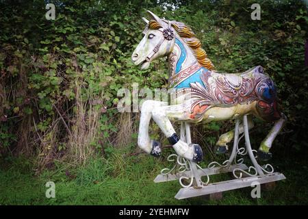 Vieux cheval en bois d'un joyeux nostalgique faire le tour debout dans une arrière-cour, altérée et partiellement recouverte de mousse mais toujours belle, espace copie, selecte Banque D'Images