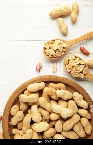 Cacahuètes fraîches et saines dans un bol et une cuillère sur fond blanc. Vue de dessus. Super aliments. Banque D'Images