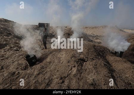 Des travailleurs palestiniens râtelent du bois brûlé sur un site de production de charbon de bois à Khan Yunis dans le Sud de la bande de Gaza des travailleurs palestiniens râtelent du bois brûlé sur un site de production de charbon de bois à Khan Yunis dans le Sud de la bande de Gaza le 30 octobre 2024 dans le cadre de la guerre en cours dans le territoire palestinien entre Israël et le Hamas. Photo de Omar Ashtawy apaimages Khan Yunis bande de Gaza territoire palestinien 311024 KhanYunis OSH 0041 Copyright : xapaimagesxOmarxAshtawyxxapaimagesx Banque D'Images