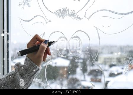 Femme peinture à la main cerf de Noël peint sur verre de fenêtre.Décoration d'hiver de Noël sur la vitre.Motif de cerf blanc.Snow art tray winpo Banque D'Images