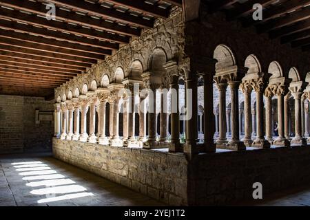 Cloître médiéval ensoleillé avec des arches en pierre et des colonnes créant une atmosphère sereine, Sta. Maria d'Estany, cloître roman, Estany, Catalogne Banque D'Images