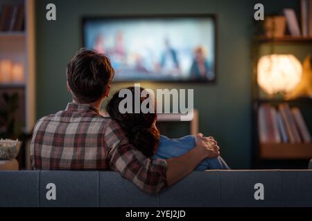 Famille heureuse regardant la télévision, films le soir à la maison. Couple passant du temps ensemble. Banque D'Images