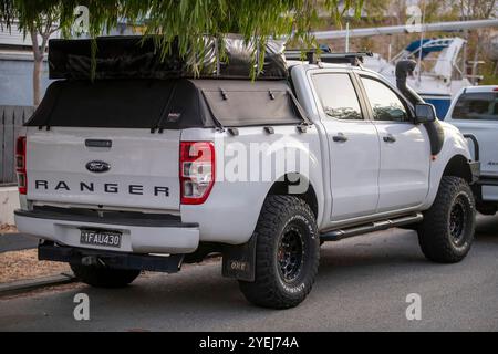 Un Ford Ranger blanc stationné dans une rue de banlieue, équipé de gros pneus hors route, d'un auvent noir, d'une galerie de toit et d'un sac de rangement sur le toit. Banque D'Images