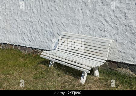 Ancien banc en bois contre un vieux mur de pierre par temps ensoleillé. Banque D'Images