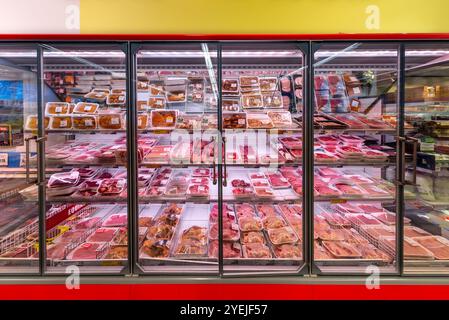 Italie - 11 octobre 2023 : viande crue de bœuf, de volaille, de porc et de cheval dans des emballages sous vide sur des étagères de vitrine réfrigérées à vendre dans un supermarché italien Banque D'Images