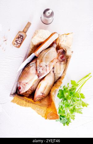 Poisson cru sur papier sur une table. Ils semblent frais et prêts à cuire. Banque D'Images