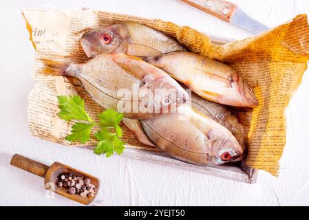 Poisson cru sur papier sur une table. Ils semblent frais et prêts à cuire. Banque D'Images