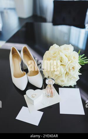 Accessoires de la mariée. Chaussures de mariage pour la mariée. Chaussures blanches à talons hauts près des anneaux de mariage, bijoux de mariage. Banque D'Images