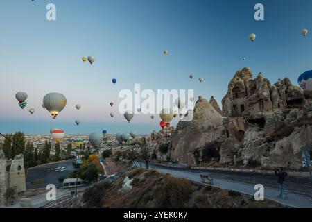 Des montgolfières colorées s'élèvent gracieusement au-dessus des formations rocheuses uniques de la Cappadoce à l'aube Banque D'Images