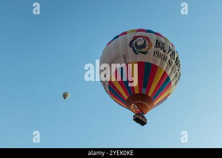 Les montgolfières montent doucement dans le ciel affichant des couleurs vives sur fond de formations rocheuses uniques de Cappadoce Banque D'Images