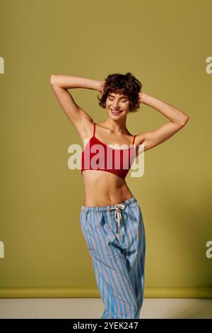 Une jeune femme joyeuse pose dans une tenue de détente élégante sur un fond vibrant. Banque D'Images