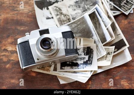 Table en bois, vintage et appareil photo avec des photographies rétro sur noir et blanc. Numérique, old School et bureau avec des images pour la créativité, le projet et Banque D'Images