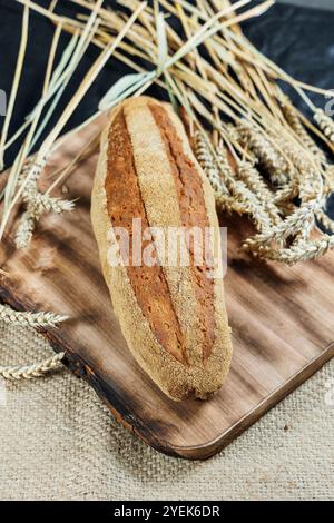 Pain de seigle fraîchement cuit sur levain sans levure et farine de grains entiers, de seigle et de blé. Il repose sur une planche à découper. Banque D'Images